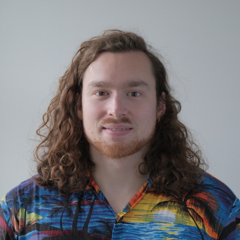 Selfie van een man met lang bruin krullend haar tot en met onder de schouder, die een hawaii shirt draagt.